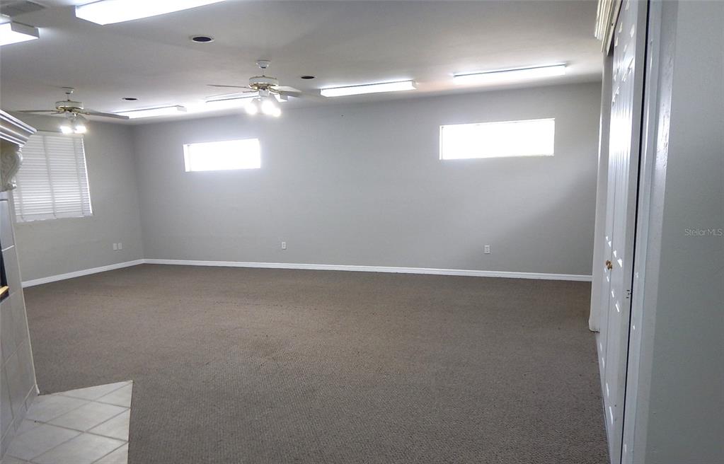 A spacious room features gray walls, carpeted flooring, ceiling fans, and rectangular windows — 3921 NW 97TH BOULEVARD UNIT 202, GAINESVILLE, FL