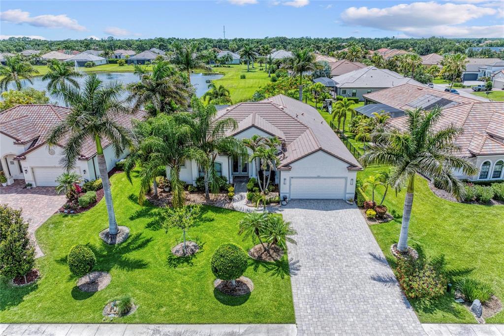 An aerial view of a single-story house with a tiled roof, driveway, and palm trees — 956 145TH STREET CIRCLE NE, BRADENTON, FL