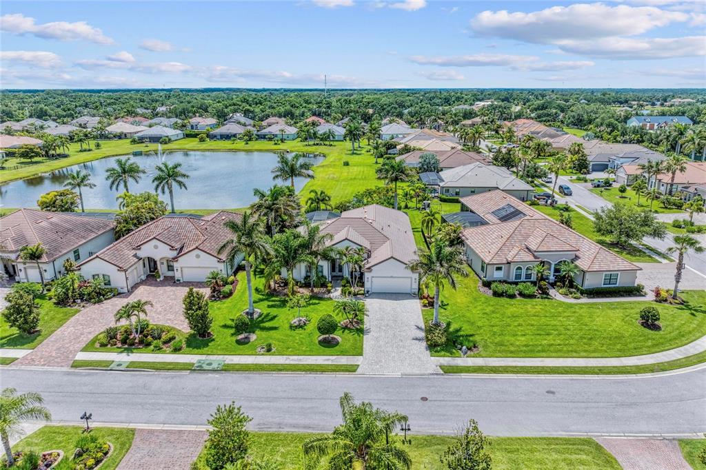 An aerial view of a suburban neighborhood featuring houses with tile roofs and palm trees — 956 145TH STREET CIRCLE NE, BRADENTON, FL
