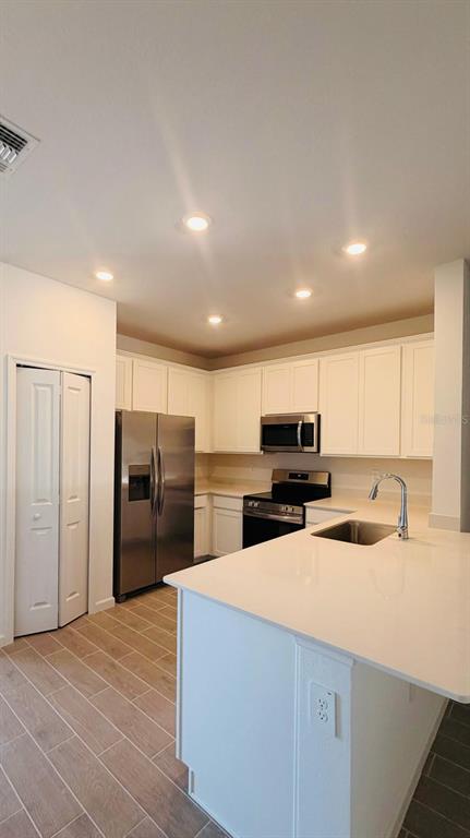 A kitchen with white cabinets, stainless steel appliances, and a quartz-topped island — 3649 SE 37TH CT UNIT CT, OCALA, FL