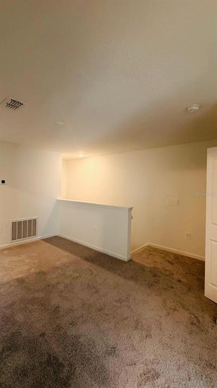 An upstairs landing area features beige carpet, white walls, and a half-wall staircase railing — 3649 SE 37TH CT UNIT CT, OCALA, FL
