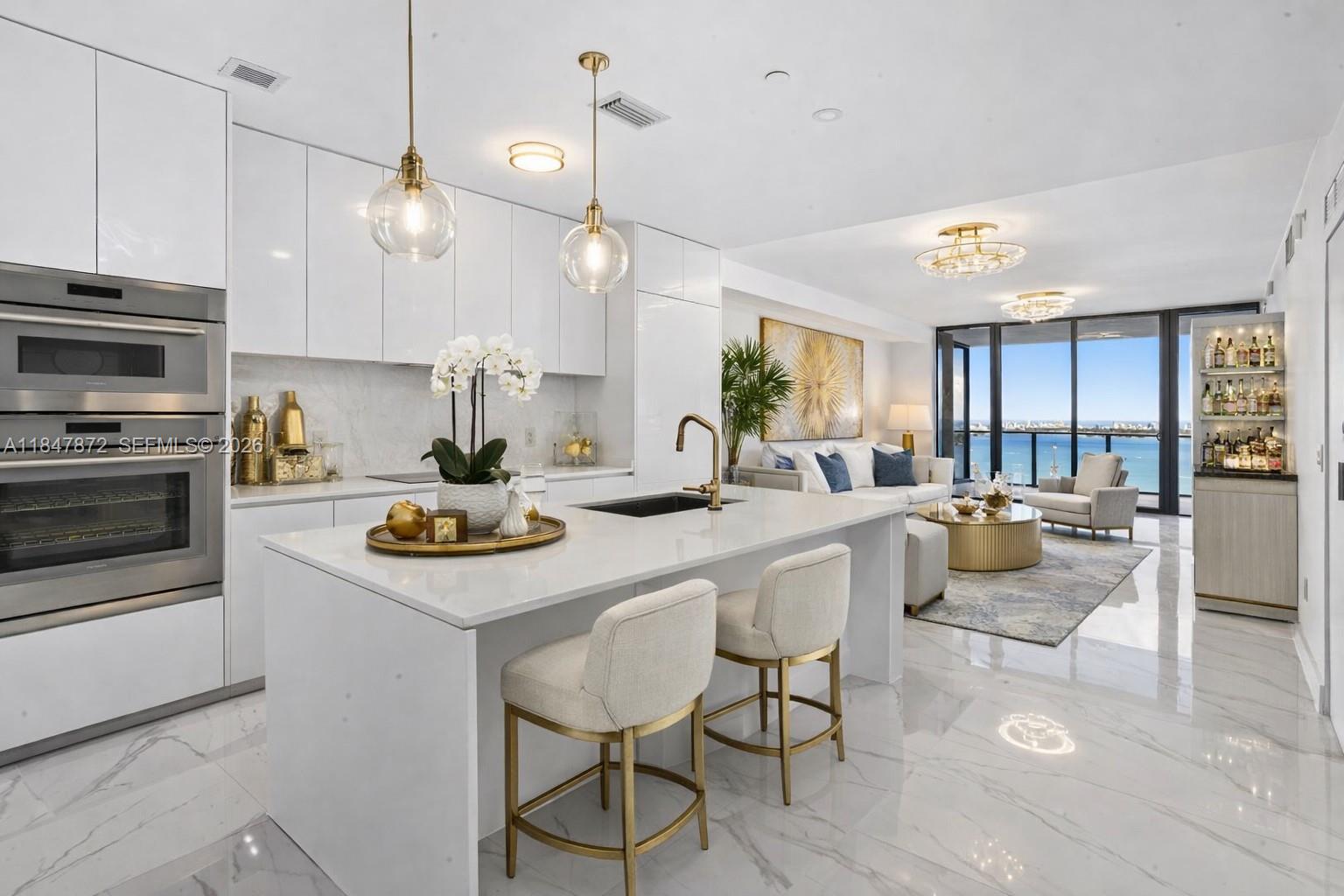 A modern open-concept kitchen and living area features white cabinetry, marble floors, and ocean views — 700 NE 24th ST # 3502, Miami FL 33137, MIAMI, FL