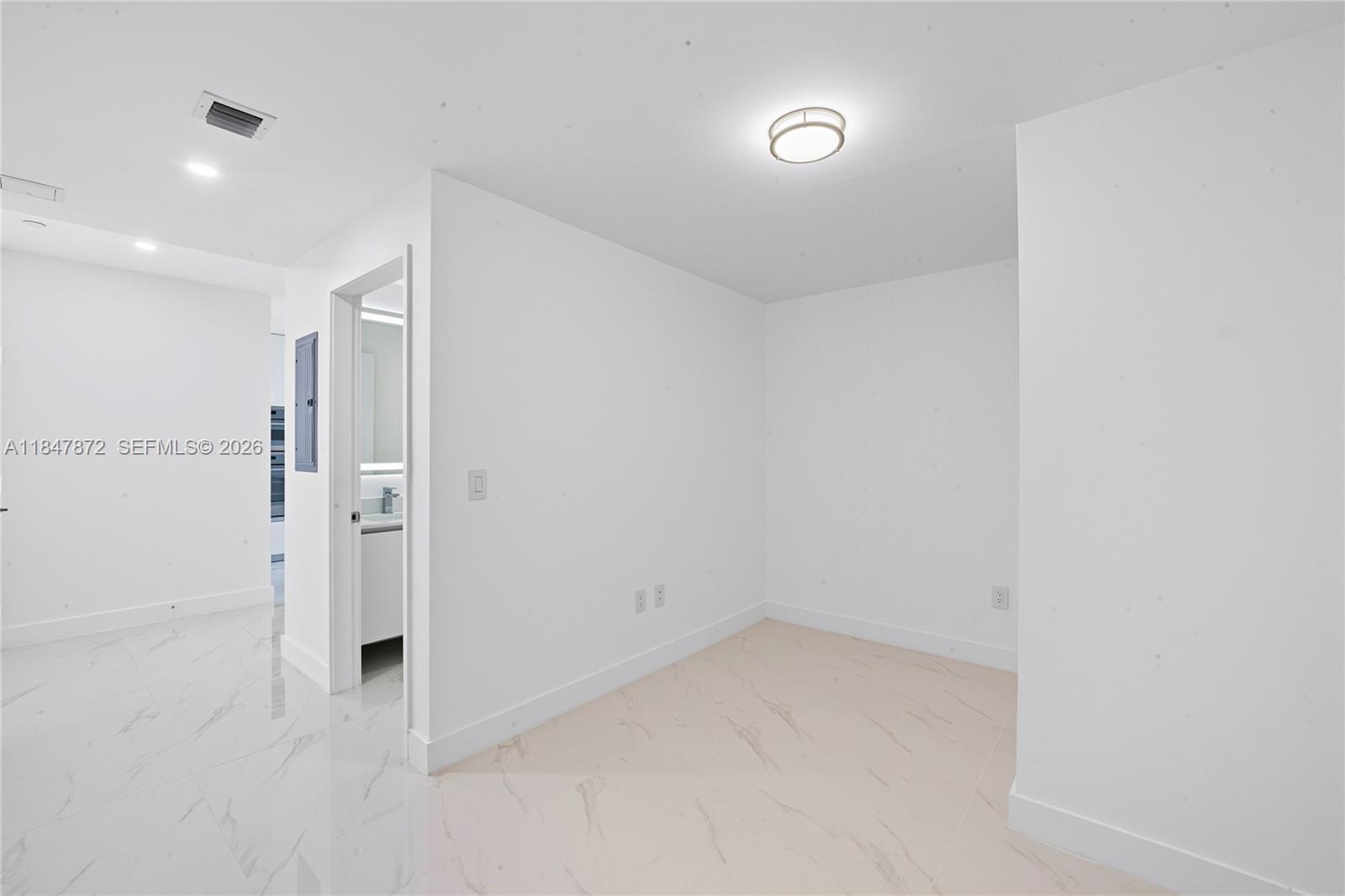 A bright, empty room features white walls, a flush-mount light fixture, and light-colored tile flooring — 700 NE 24th ST # 3502, Miami FL 33137, MIAMI, FL