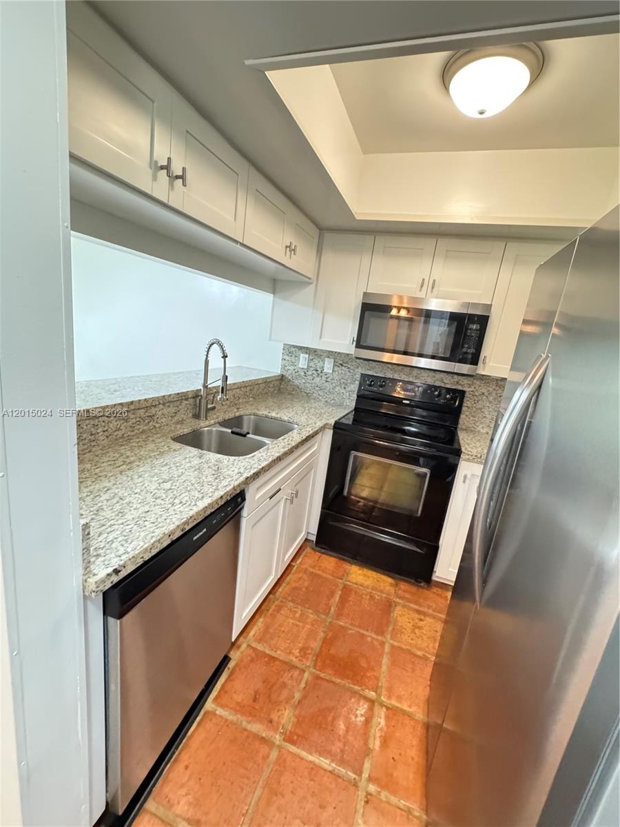 A two-story tan stucco apartment building features a balcony, wooden fencing, and outdoor mailboxes — 8999 SW 123rd Ct # 112, Miami FL 33186, MIAMI, FL
