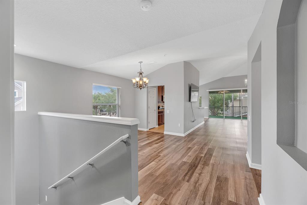 An interior view shows a living area with wood-look flooring, vaulted ceilings, and a chandelier — 2223 KINGS PALACE DRIVE UNIT 00, RIVERVIEW, FL