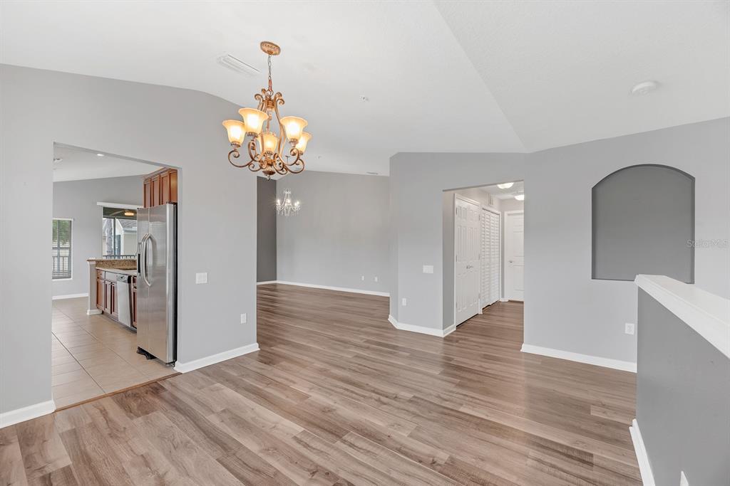 A living area with wood-look flooring, a chandelier, and an adjacent kitchen with stainless appliances — 2223 KINGS PALACE DRIVE UNIT 00, RIVERVIEW, FL