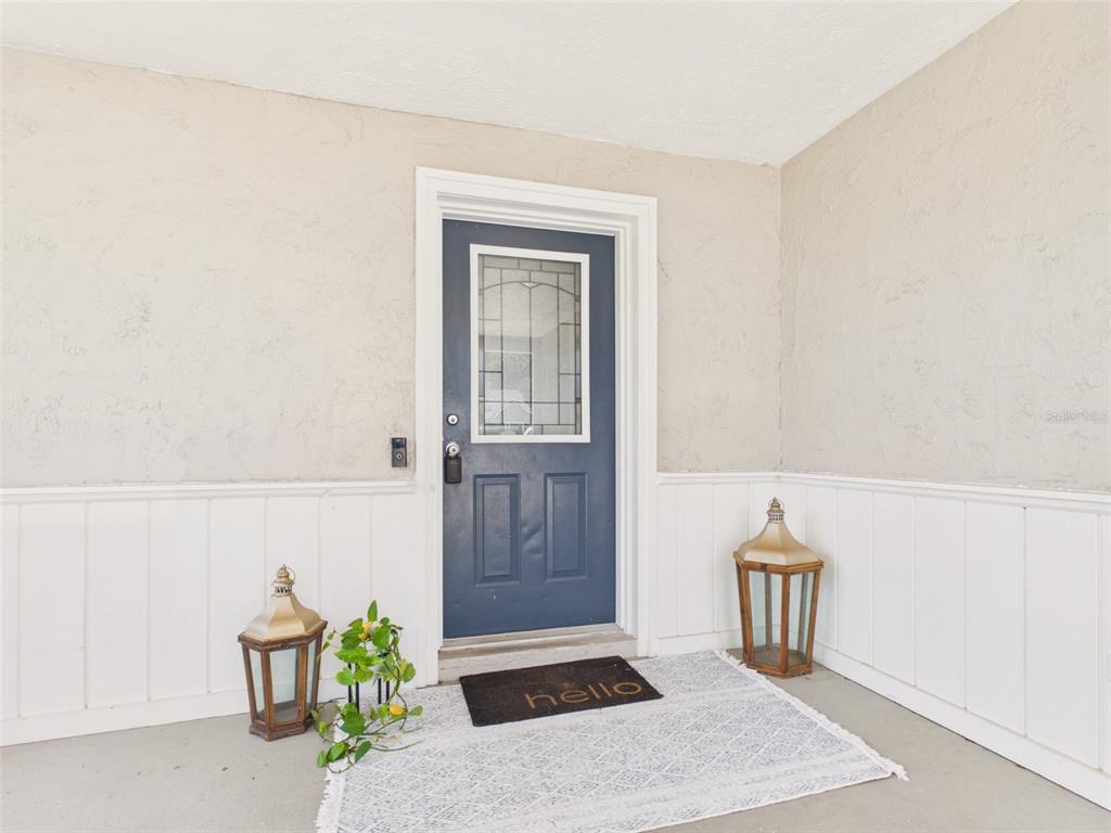 A blue front door with a glass insert sits on a covered porch with wainscoting — 37207 MCMINN AVENUE, DADE CITY, FL