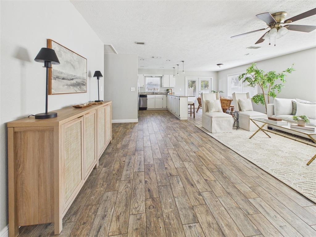 An open-concept living area features wood-look tile flooring, a light-toned sideboard, and a kitchen — 37207 MCMINN AVENUE, DADE CITY, FL