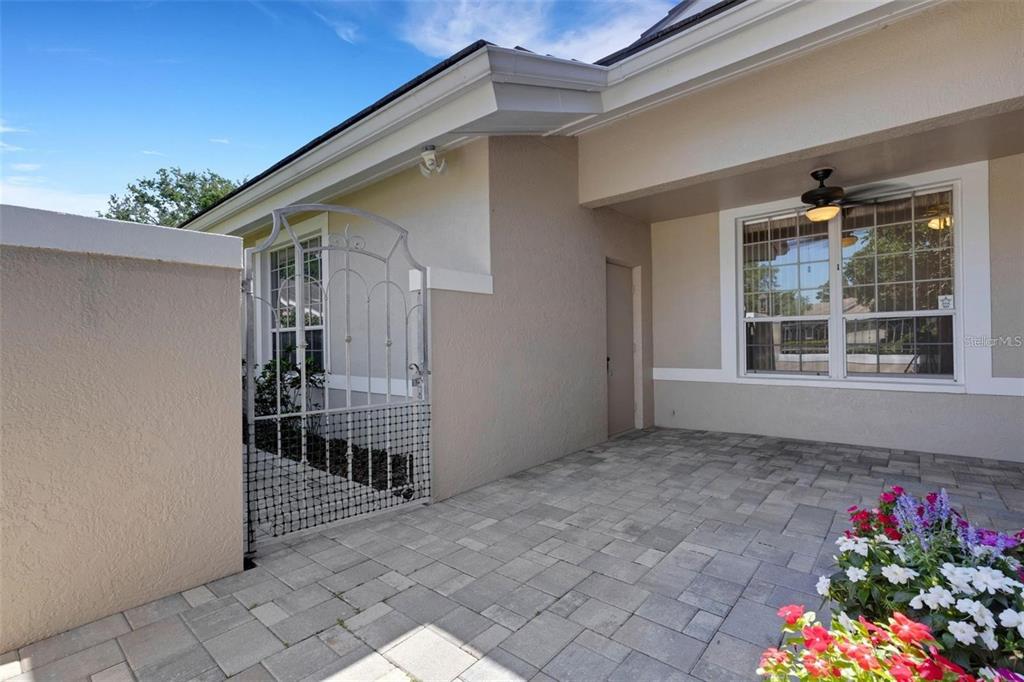 A paved patio area features a decorative metal gate and a window with a ceiling fan — 4044 PENSHURST PARK, SARASOTA, FL