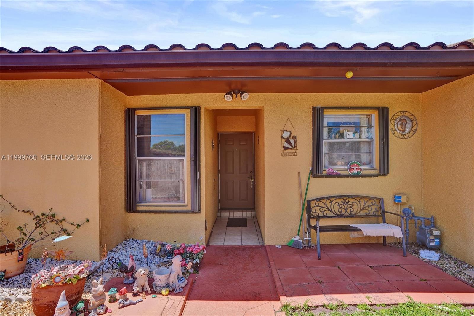 The exterior of a house features a yellow stucco wall, a front door, and a patio — 8618 SW 148th Pl, Miami FL 33193, MIAMI, FL