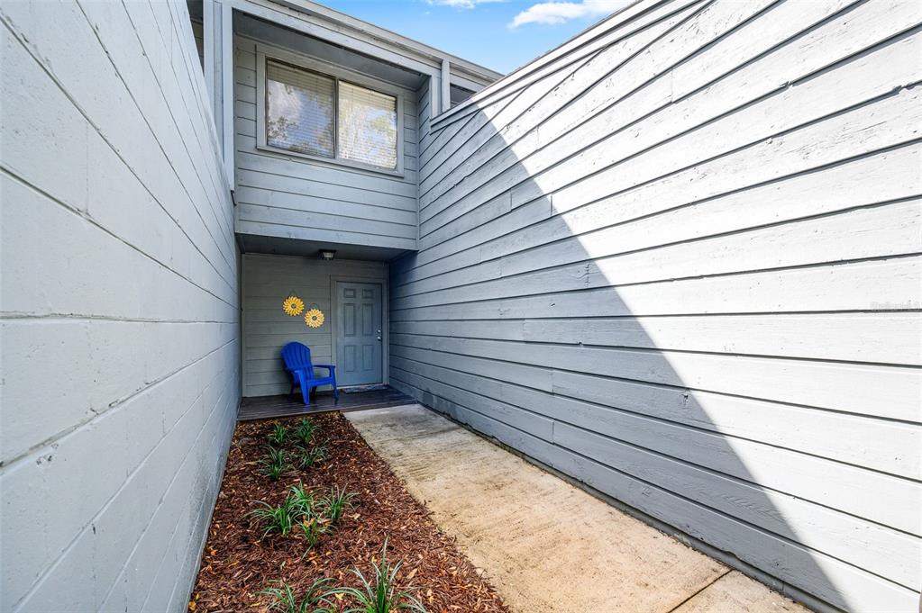 A blue chair sits on a porch next to a gray door and siding — 3012 NW 28TH CIRCLE, GAINESVILLE, FL