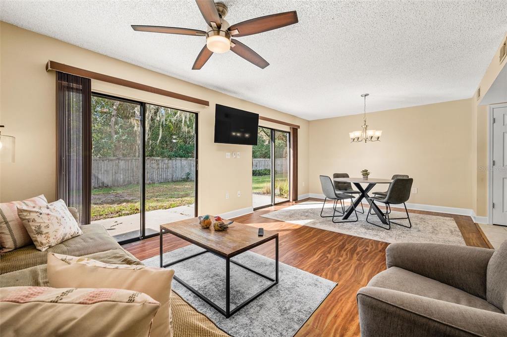 A living and dining area with wood-look flooring, a ceiling fan, and sliding glass doors — 3012 NW 28TH CIRCLE, GAINESVILLE, FL