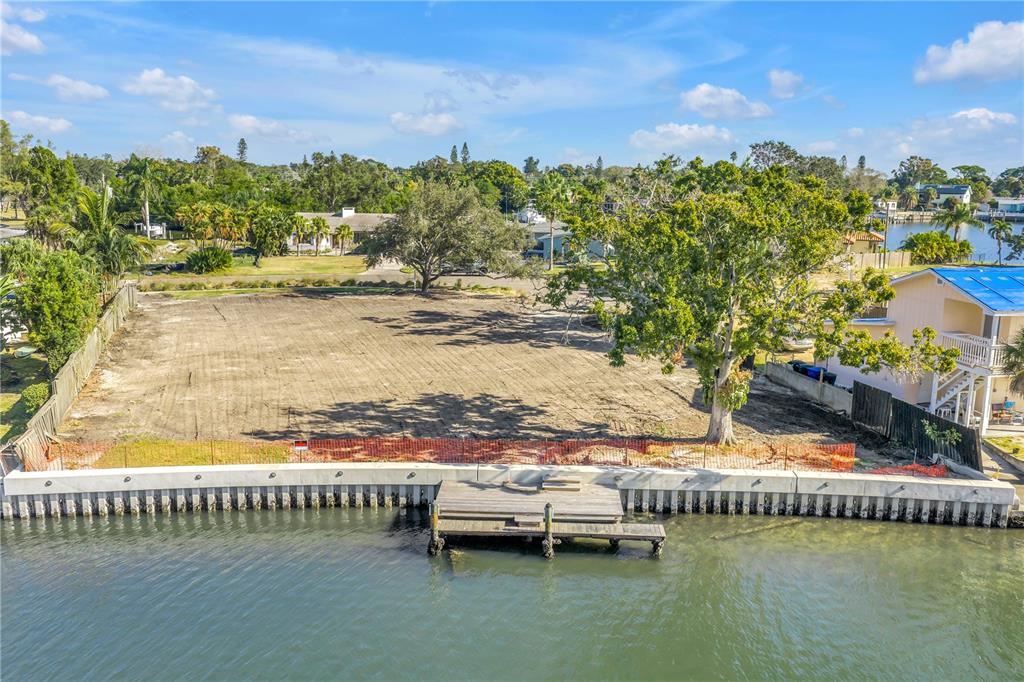 An aerial view of a cleared waterfront lot featuring a concrete seawall and wooden dock — 4811 PARADISE WAY S, ST PETERSBURG, FL