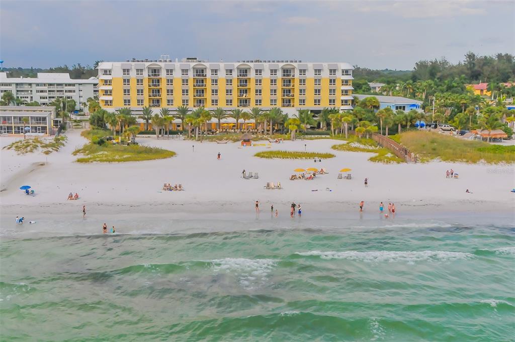 An aerial view of a multi-story yellow hotel building situated directly on a sandy beach — 915 SEASIDE DRIVE UNIT 511, Weeks 16-17, SARASOTA, FL