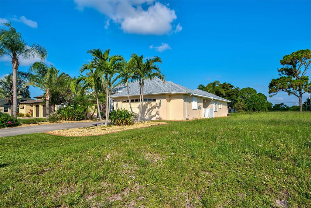 A single-story house with a beige exterior, a two-car garage, and palm trees in the yard — 956 BOUNDARY BOULEVARD, ROTONDA WEST, FL