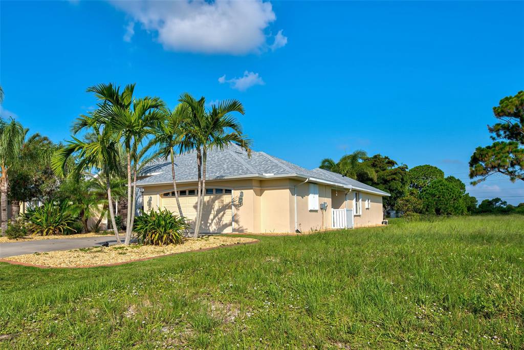 A single-story house with a beige exterior, a gray shingled roof, and palm trees — 956 BOUNDARY BOULEVARD, ROTONDA WEST, FL