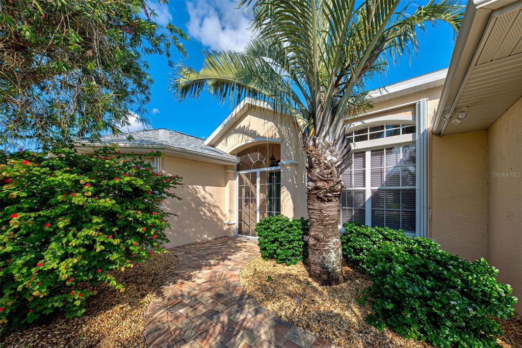 A paved walkway leads to the front entrance of a house with a palm tree — 956 BOUNDARY BOULEVARD, ROTONDA WEST, FL