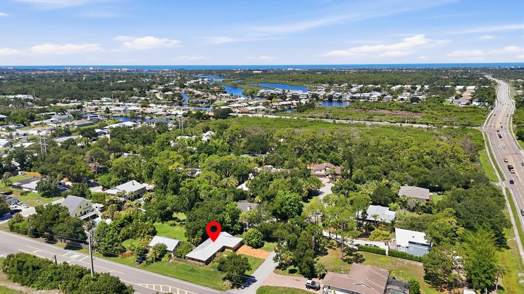 An aerial view shows a residential house with a red location pin on a lot — 1700 SPOONBILL DRIVE, NOKOMIS, FL