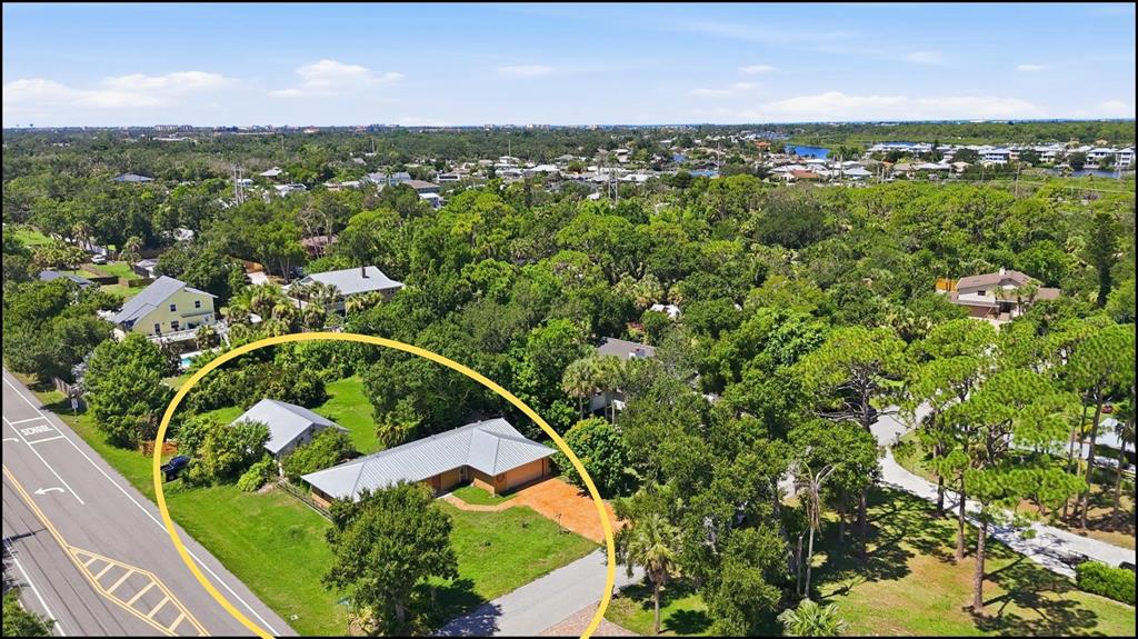 An aerial view shows a single-story house with a metal roof and a large yard — 1700 SPOONBILL DRIVE, NOKOMIS, FL
