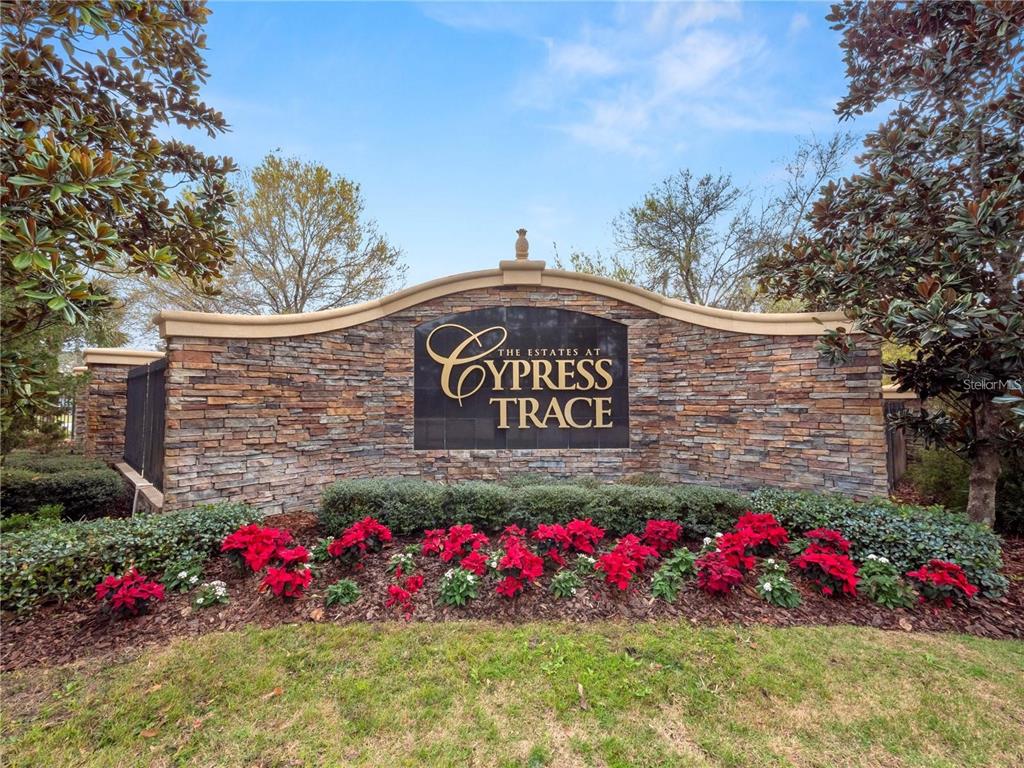 A stone monument sign for The Estates at Cypress Trace sits behind red poinsettia plants — CYPRESS TRACE BOULEVARD, LAKELAND, FL