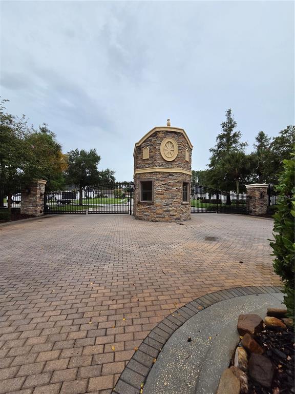 A gated entrance features stone pillars, black metal fencing, and a central guardhouse — CYPRESS TRACE BOULEVARD, LAKELAND, FL