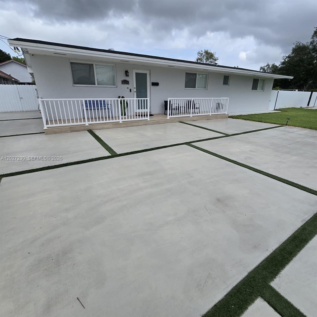 A single-story house features a white exterior, a front porch with white railings, and a concrete driveway — 10245 SW 68th St # 10245, Miami FL 33173, MIAMI, FL