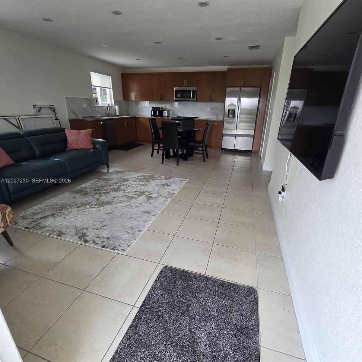 An open-concept living area features a kitchen with wood cabinets and a dark sofa — 10245 SW 68th St # 10245, Miami FL 33173, MIAMI, FL