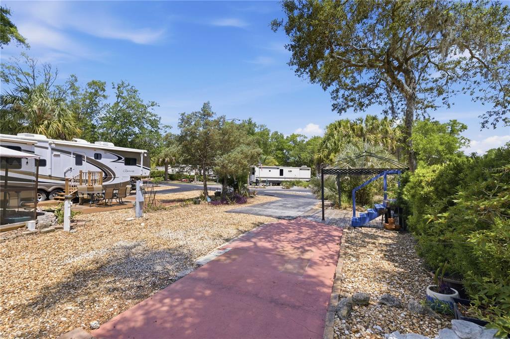 A gravel lot features a paved walkway, a metal gazebo, and two parked recreational vehicles — 10173 N SUNCOAST BOULEVARD UNIT 80, CRYSTAL RIVER, FL