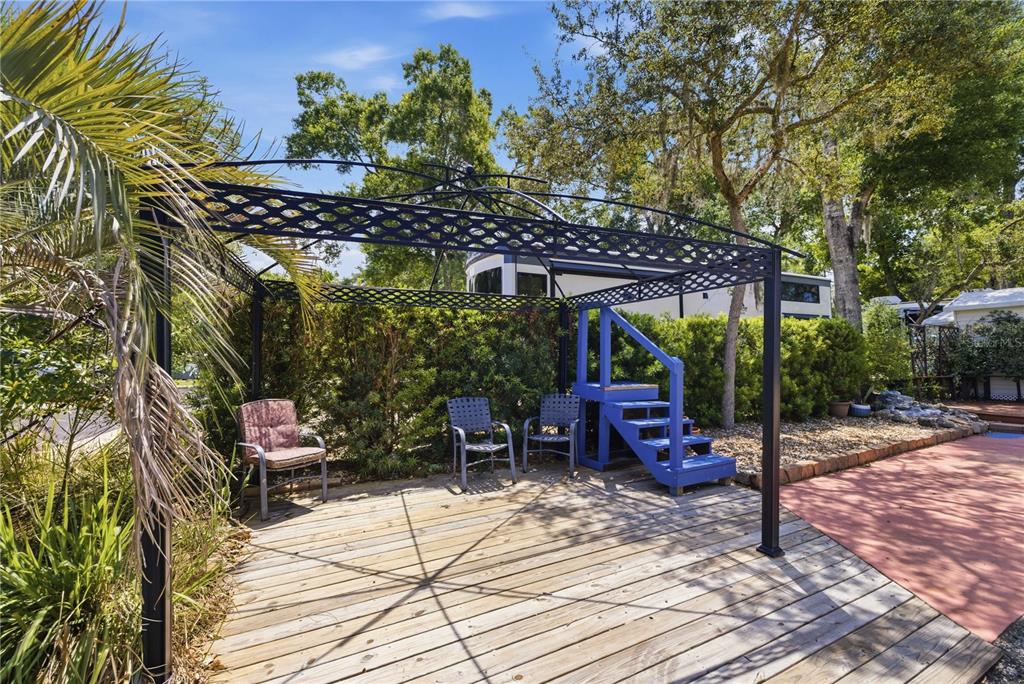 A wooden deck features a black metal gazebo, three chairs, and blue wooden steps — 10173 N SUNCOAST BOULEVARD UNIT 80, CRYSTAL RIVER, FL