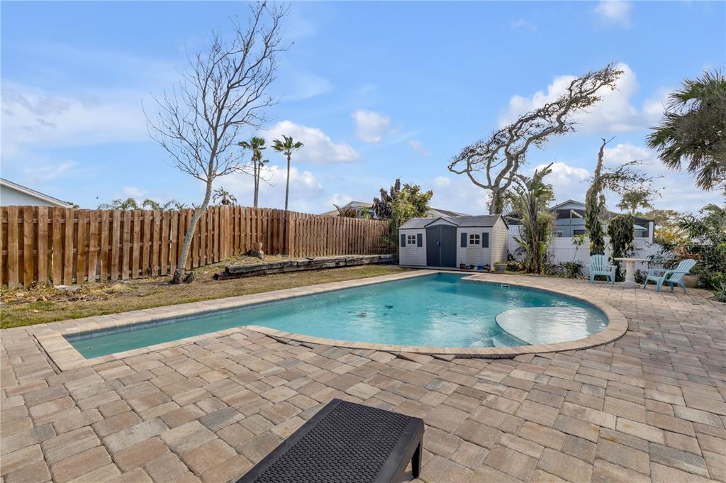 A backyard features a swimming pool with a tanning ledge, paver patio, and wooden fence — 831 E 21ST AVENUE, NEW SMYRNA BEACH, FL