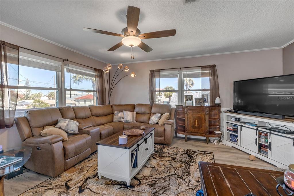 A living room features a brown sectional sofa, a coffee table, and a television console — 831 E 21ST AVENUE, NEW SMYRNA BEACH, FL