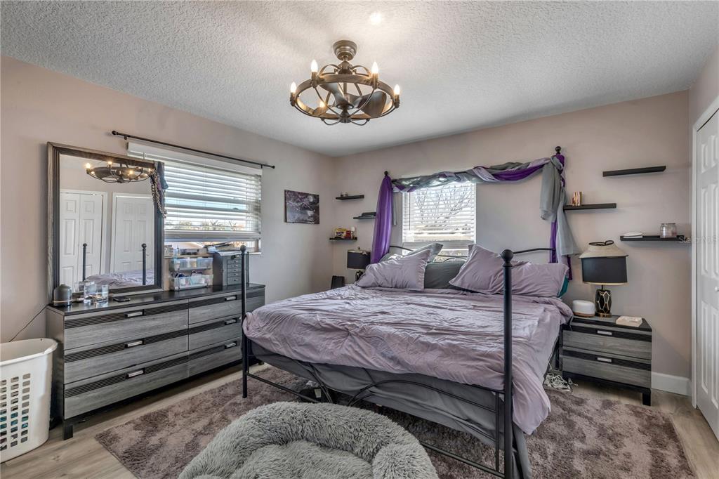 A bedroom features a metal-framed bed, gray wood-grain furniture, purple accents, and a ceiling fan — 831 E 21ST AVENUE, NEW SMYRNA BEACH, FL