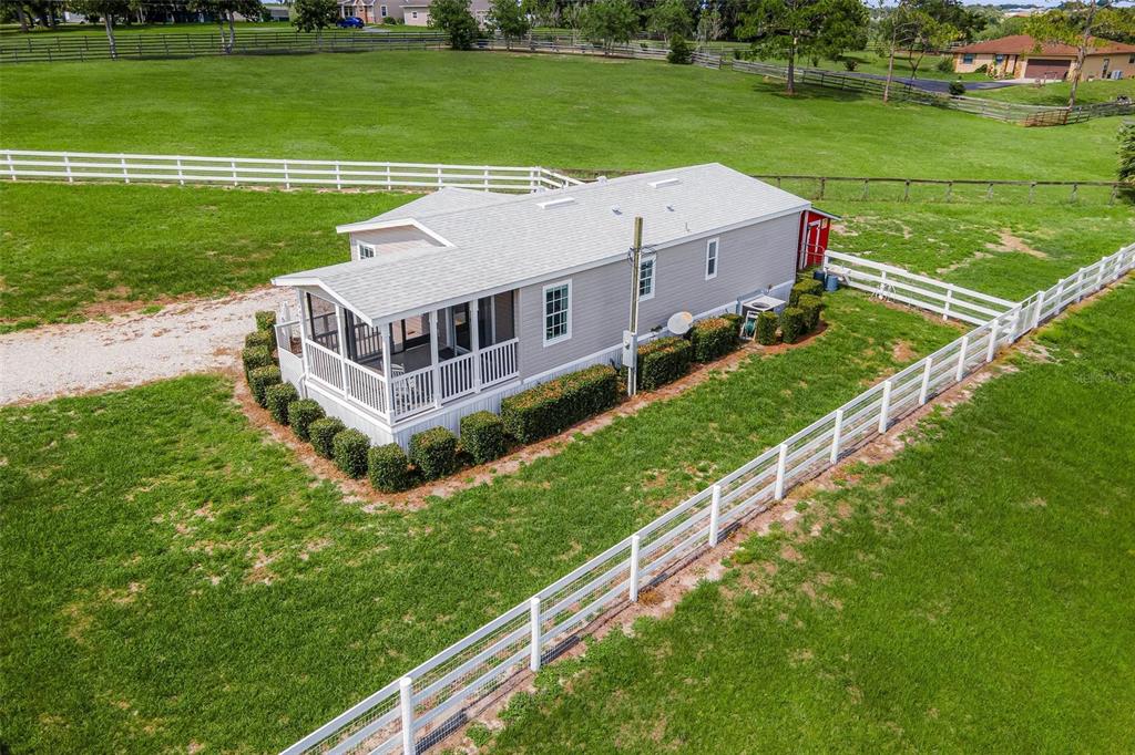 An aerial view of a single-story house with a screened porch and white perimeter fencing — 4400 LITTLE CRITTER TRAIL, LADY LAKE, FL