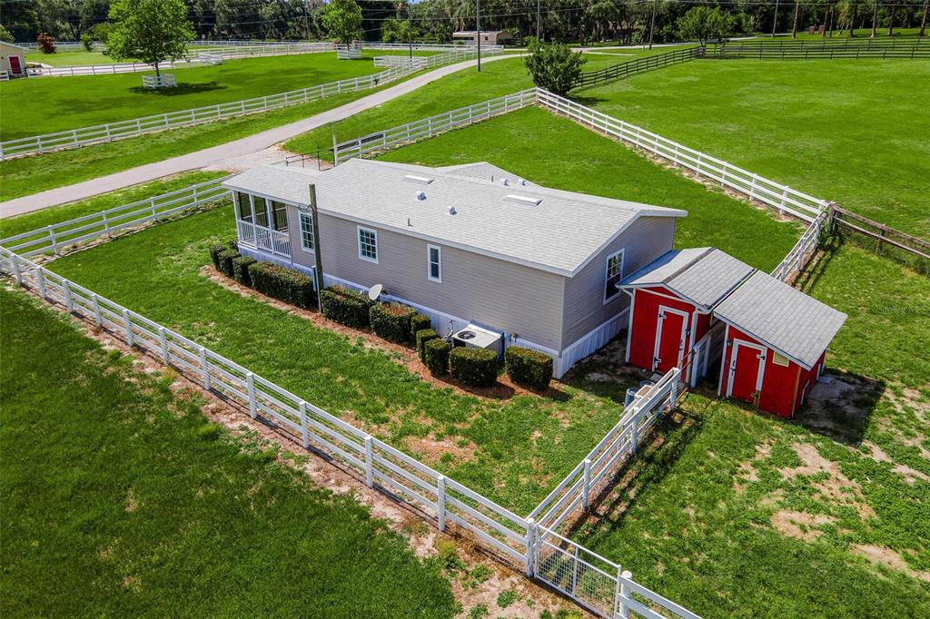 An aerial view shows a tan manufactured home with a red shed in a fenced pasture — 4400 LITTLE CRITTER TRAIL, LADY LAKE, FL
