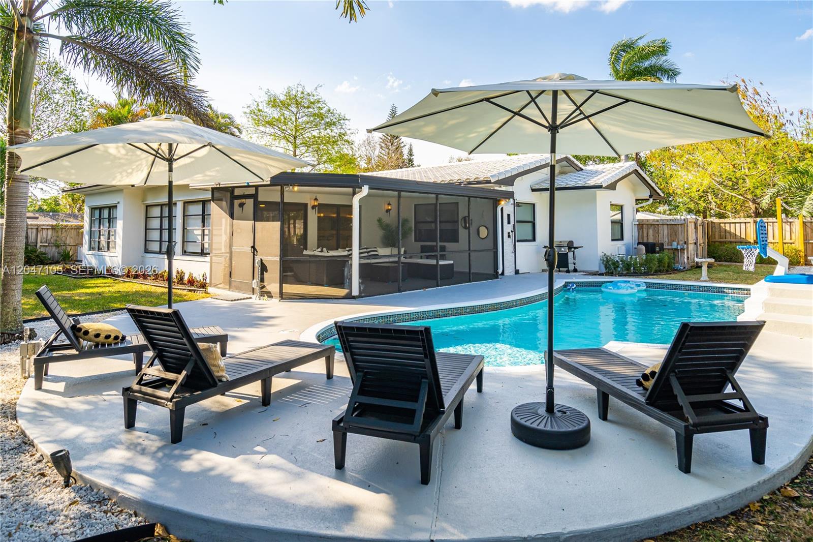 A backyard features a swimming pool, lounge chairs, patio umbrellas, and a screened-in porch — 714 NE 2nd St, Pompano Beach FL 33060, POMPANO BEACH, FL
