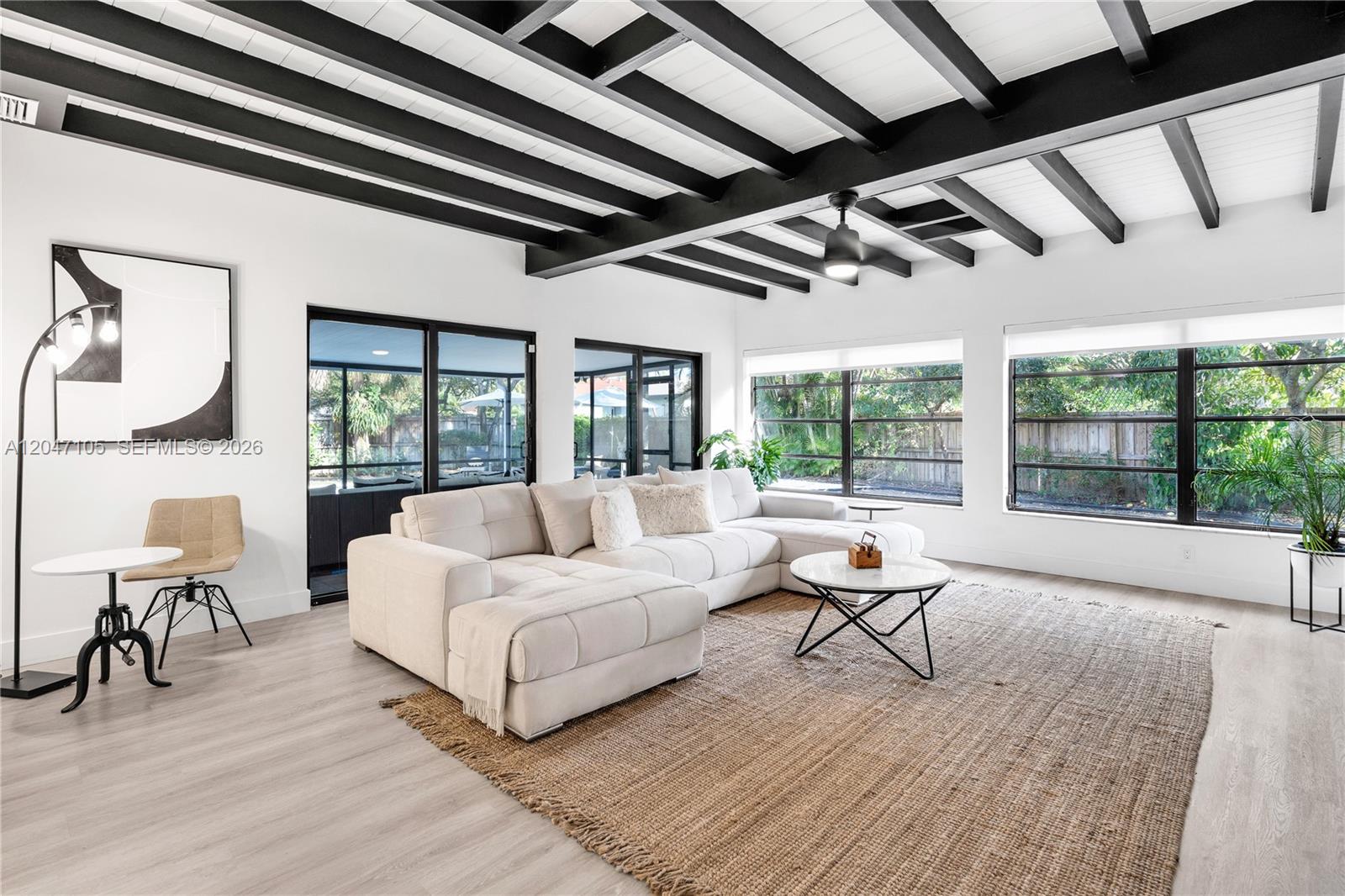 A living room features a white sectional sofa, a jute rug, and exposed black ceiling beams — 714 NE 2nd St, Pompano Beach FL 33060, POMPANO BEACH, FL