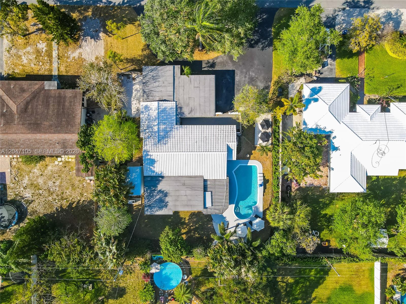 An aerial view shows a house with a swimming pool and surrounding trees — 714 NE 2nd St, Pompano Beach FL 33060, POMPANO BEACH, FL