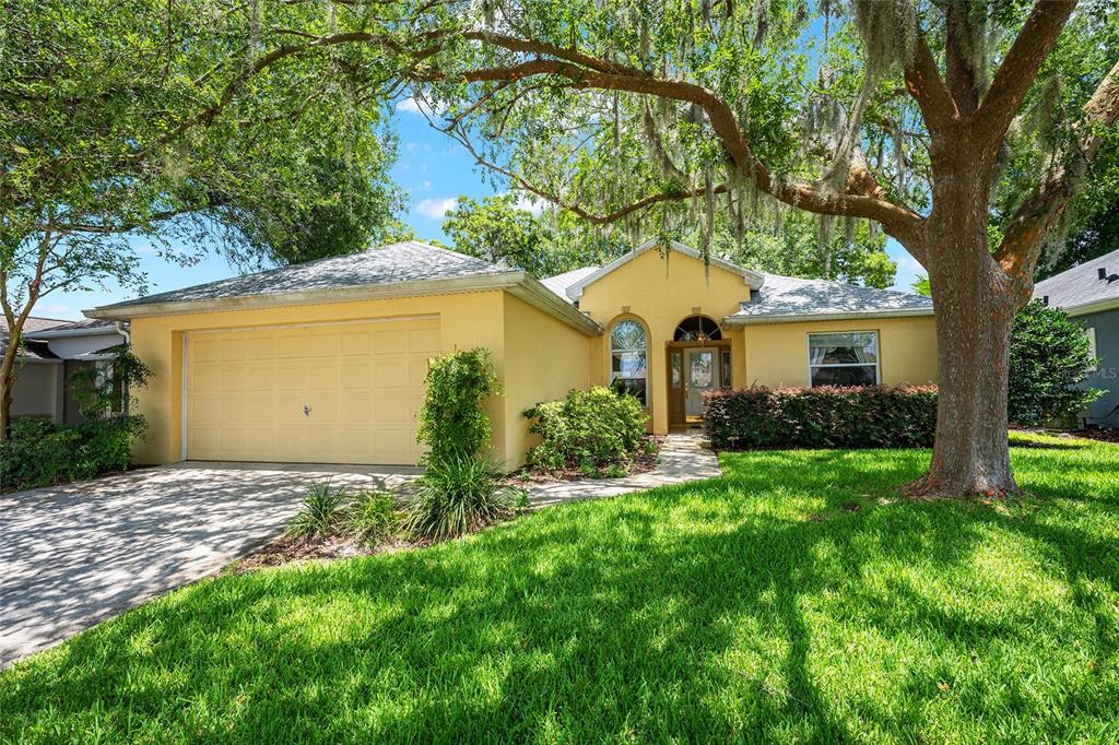 A yellow single-story house with a two-car garage and a large tree in the yard — 11262 SW 73RD CIRCLE, OCALA, FL