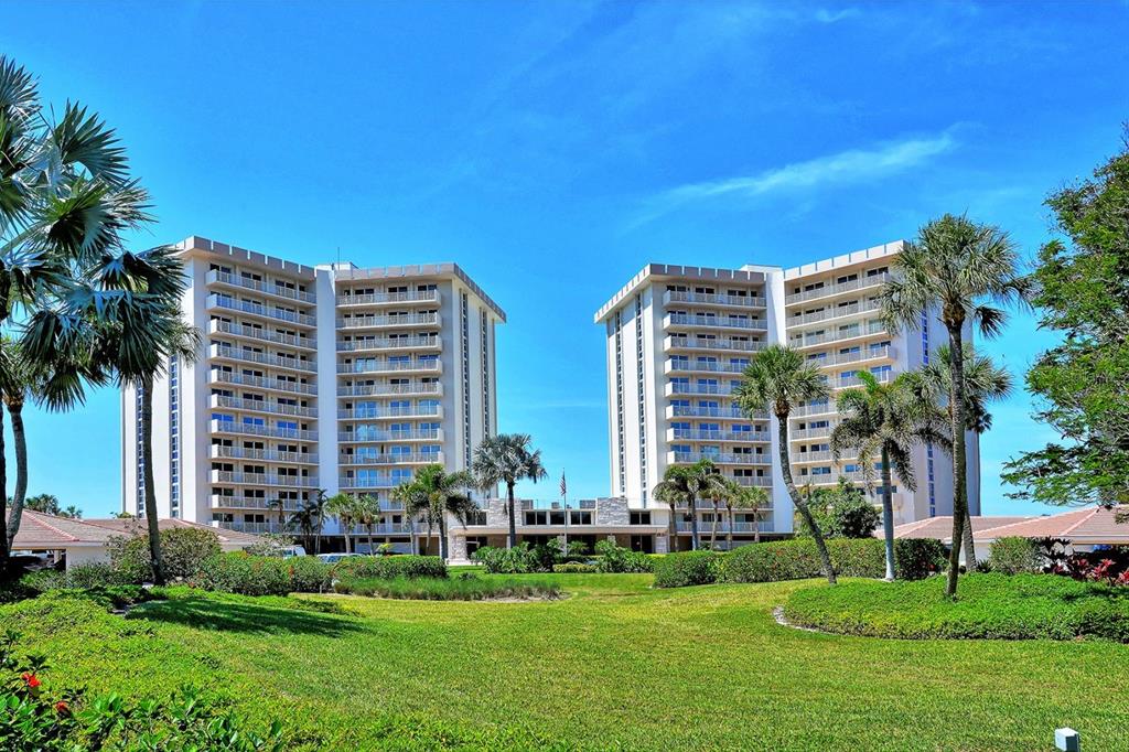 Two tall residential buildings stand behind a large green lawn with palm trees — 2301 GULF OF MEXICO DRIVE UNIT 12N and 11N, LONGBOAT KEY, FL