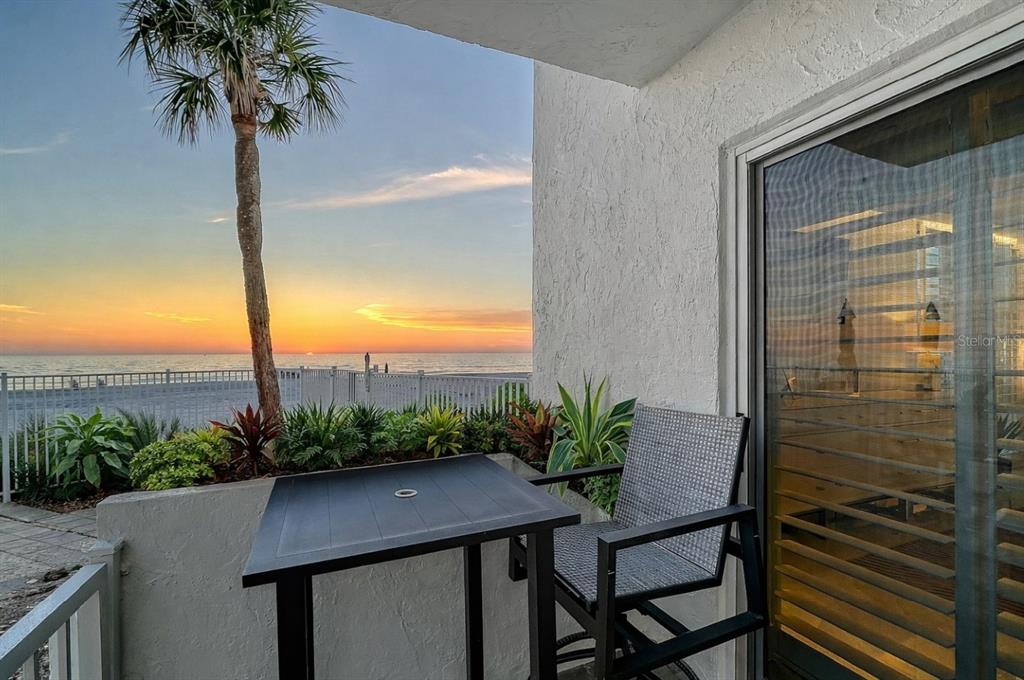 A balcony with a table and chair overlooks a beach at sunset — 2301 GULF OF MEXICO DRIVE UNIT 12N and 11N, LONGBOAT KEY, FL