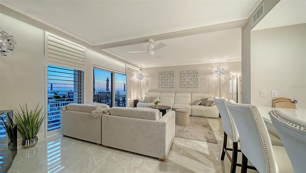 A bright living room features light-colored furniture, tile flooring, and a view of the ocean — 2301 GULF OF MEXICO DRIVE UNIT 12N and 11N, LONGBOAT KEY, FL