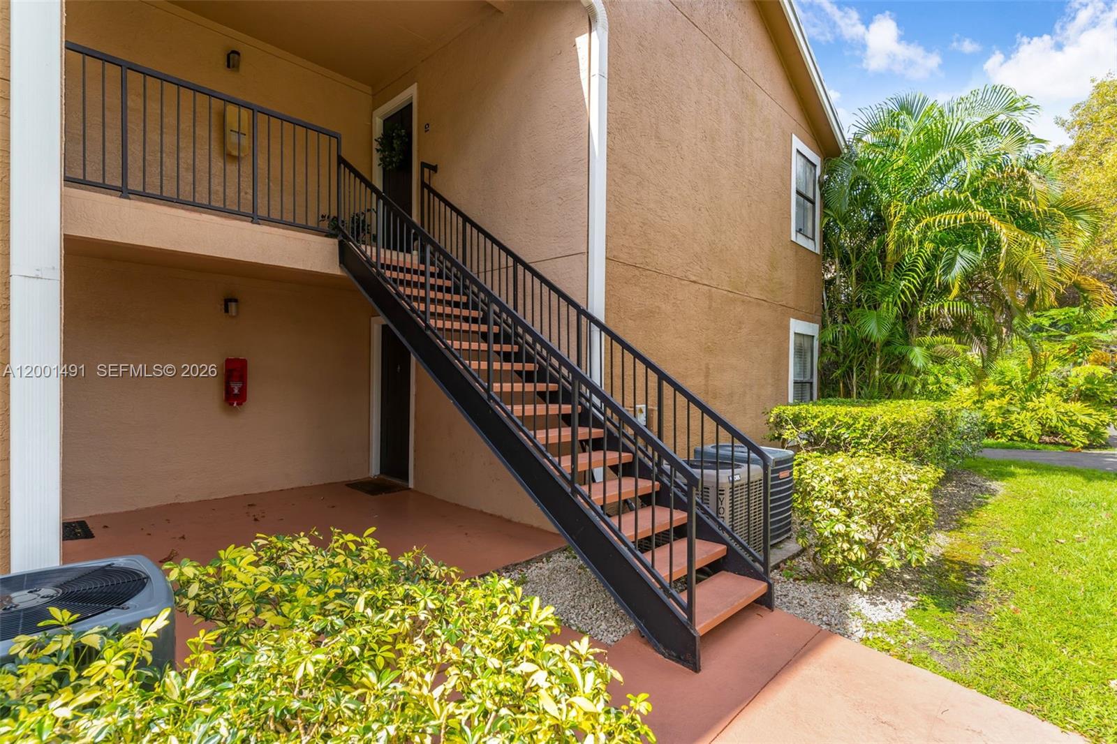 An exterior view shows a tan building with a metal staircase leading to an upper balcony — 10680 SW 155th Pl # 1405, Miami FL 33196, MIAMI, FL