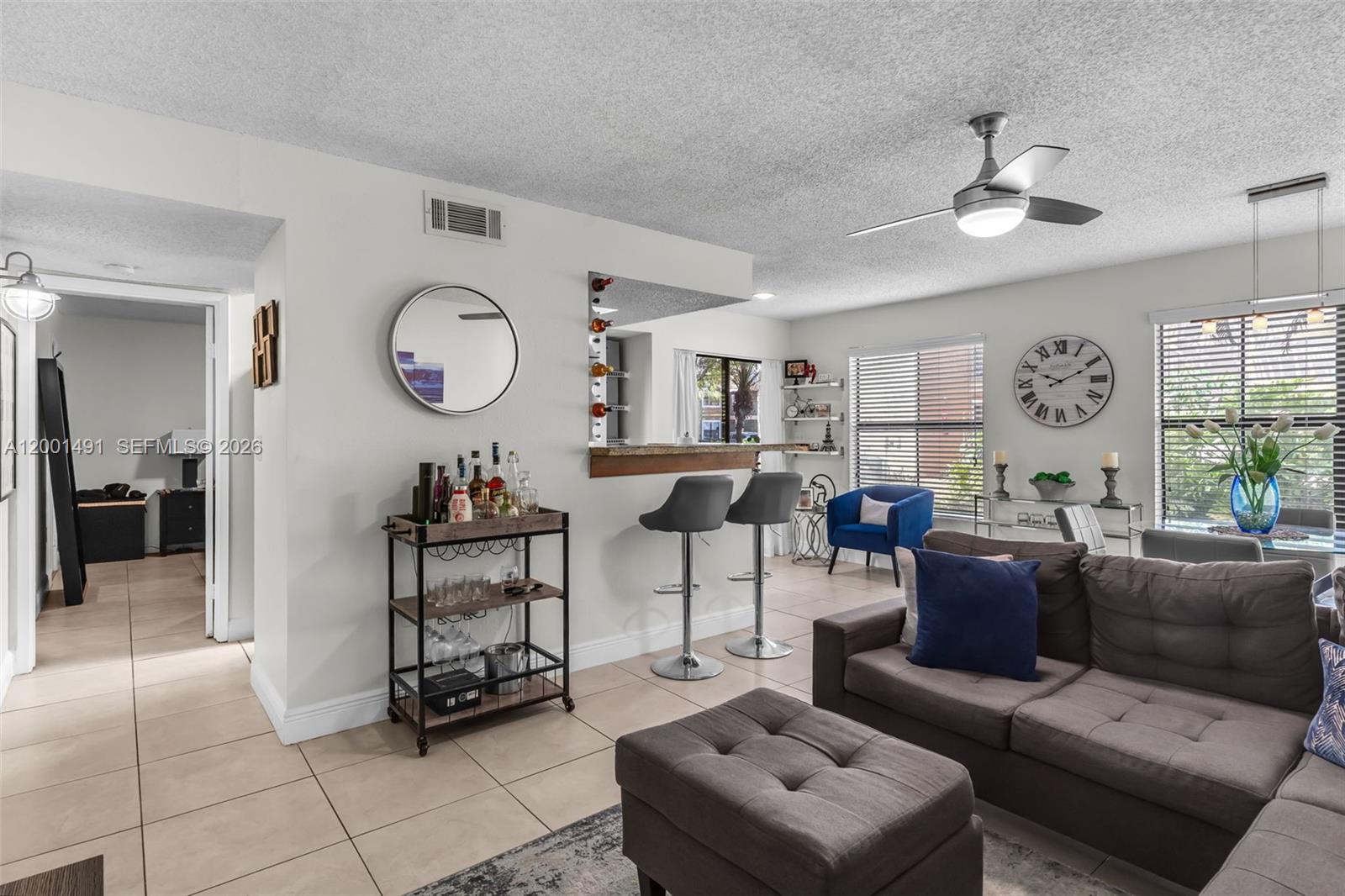 A living room features a bar area, gray sofa, ottoman, and a ceiling fan — 10680 SW 155th Pl # 1405, Miami FL 33196, MIAMI, FL