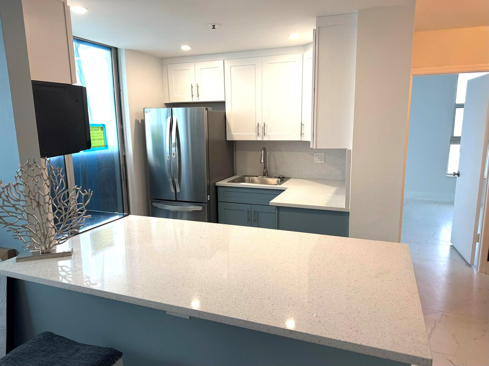 A kitchen features white upper cabinets, blue lower cabinets, stainless steel appliances, and quartz countertops — 1505 N Riverside Drive # 508, Pompano Beach FL 33062, POMPANO BEACH, FL