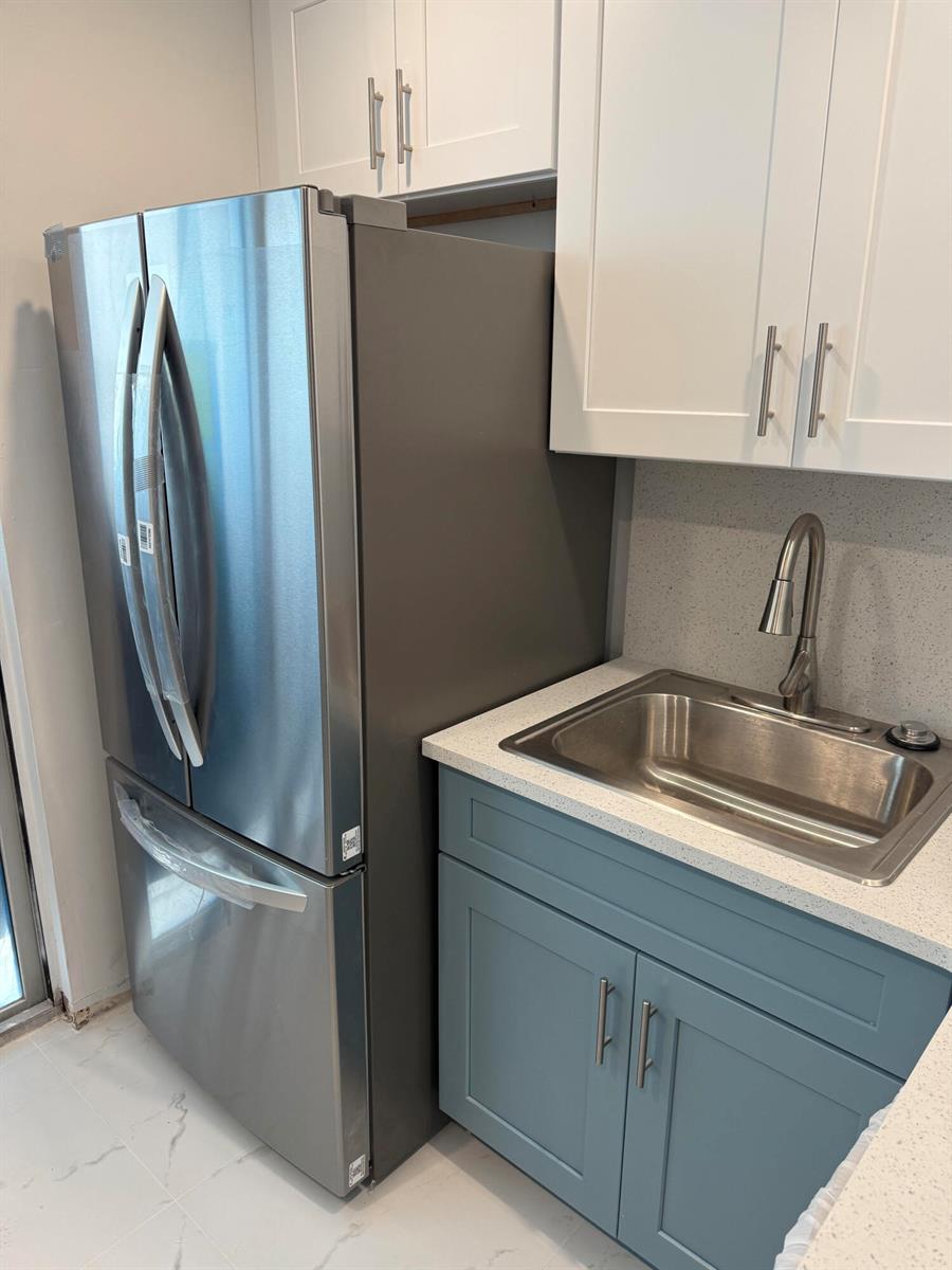 A stainless steel refrigerator stands next to a blue cabinet with a sink and countertop — 1505 N Riverside Drive # 508, Pompano Beach FL 33062, POMPANO BEACH, FL