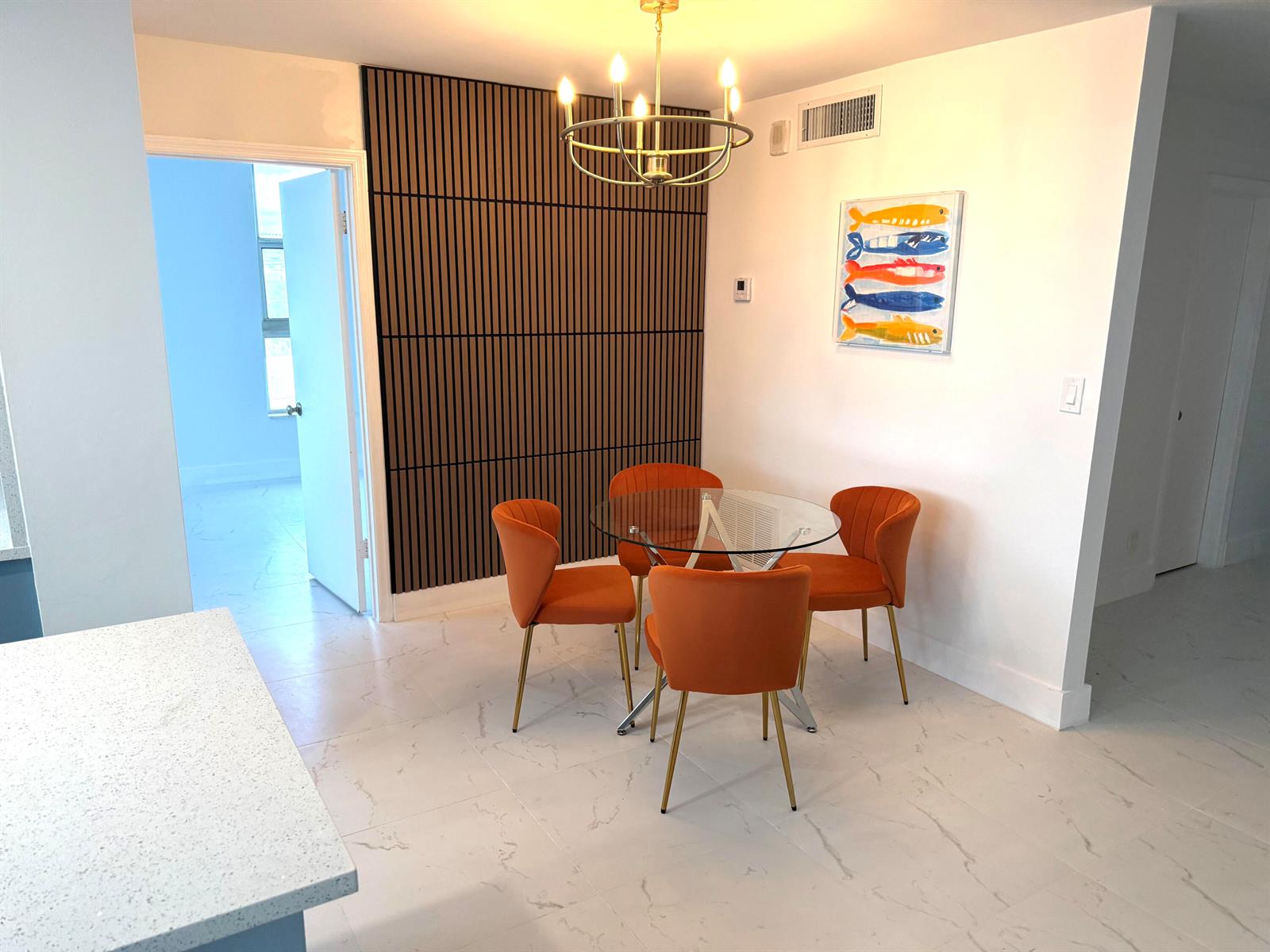 A dining area features a glass table, four orange chairs, and a wood-slatted accent wall — 1505 N Riverside Drive # 508, Pompano Beach FL 33062, POMPANO BEACH, FL