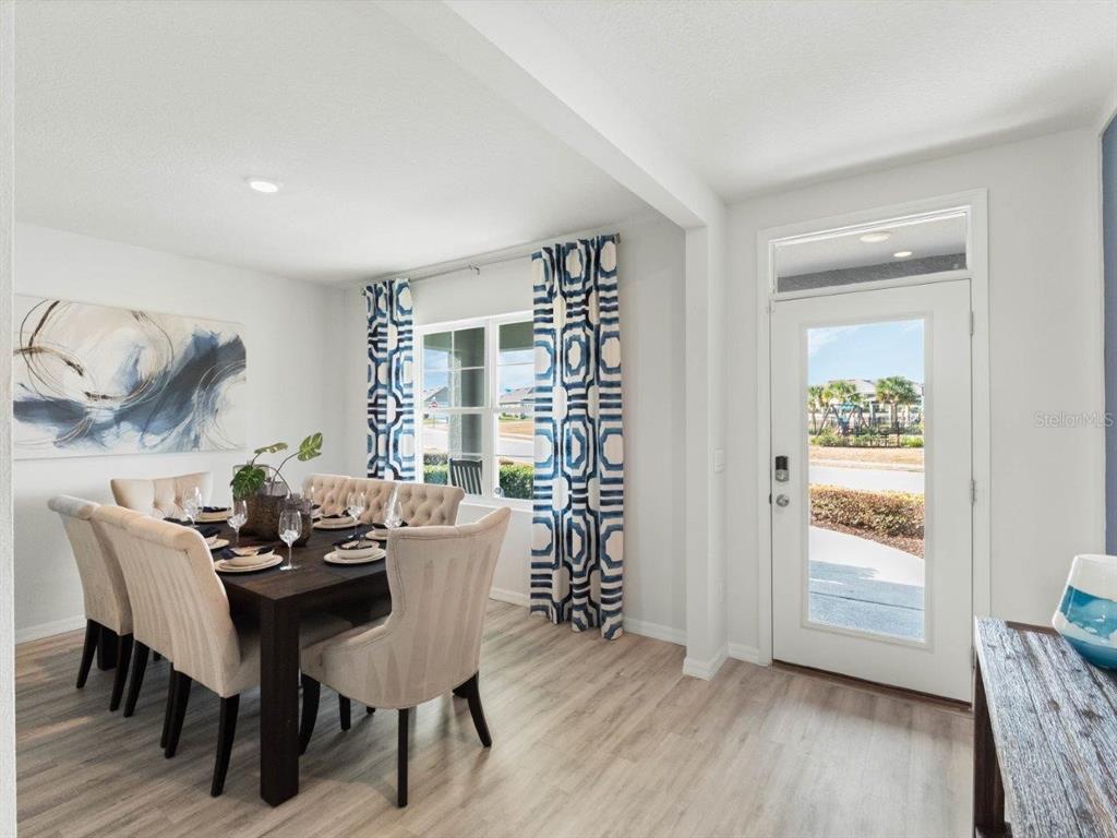A dining room features a dark wood table, upholstered chairs, patterned curtains, and a glass-paneled door — 7858 FORREST FOX WAY, LAKELAND, FL