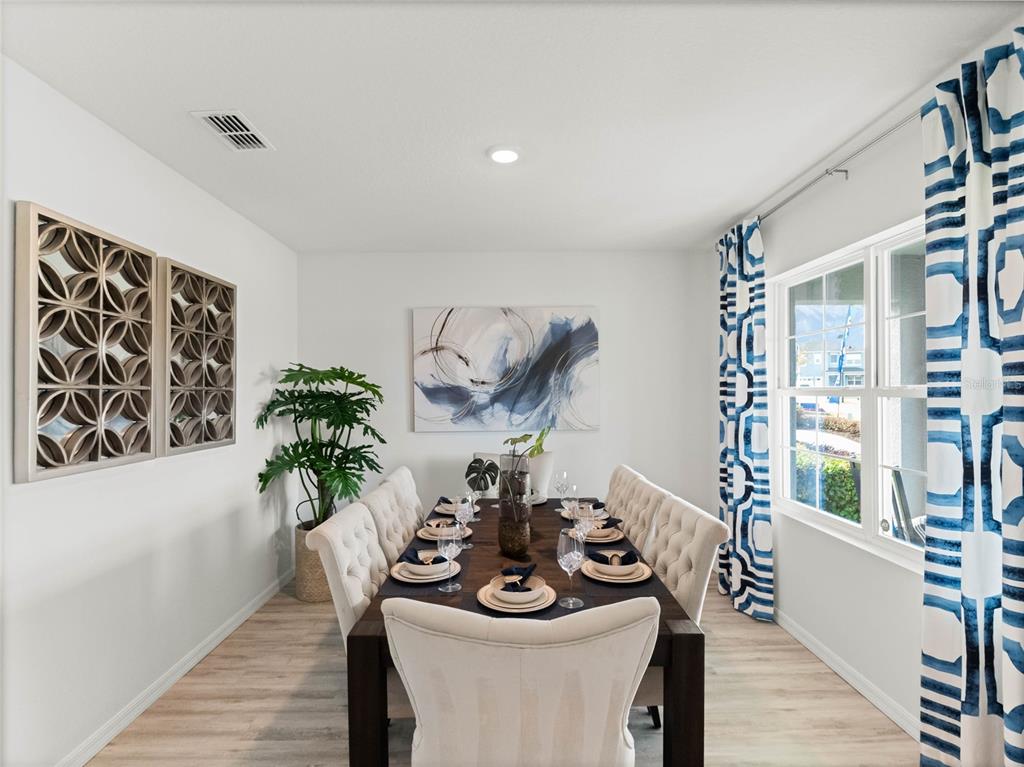 A dining room features a dark wood table, tufted chairs, patterned curtains, and wall art — 7858 FORREST FOX WAY, LAKELAND, FL