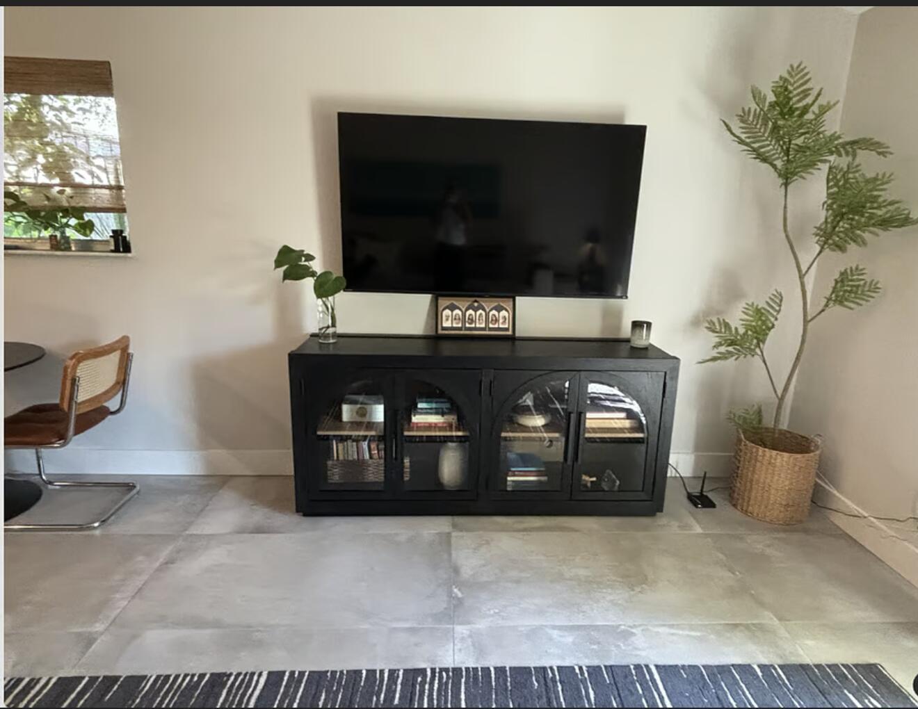 A living room features a wall-mounted television above a black arched-glass media console and plant — 1822 Windsor # 1, FL 33408, FL