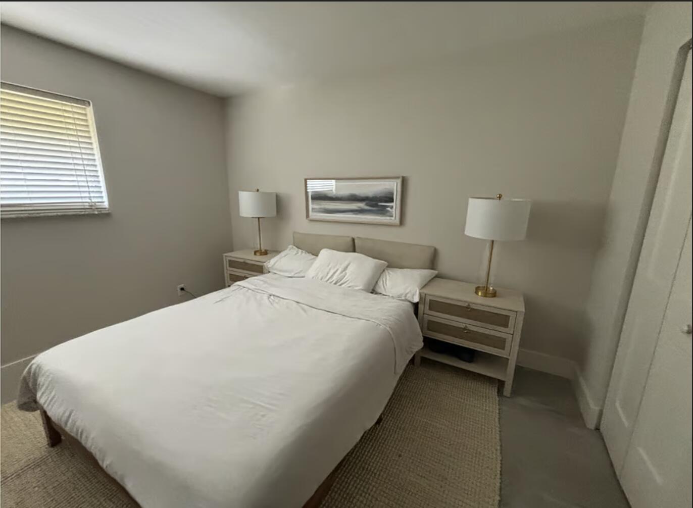 A bedroom features a bed with white bedding, two nightstands with lamps, and wall art — 1822 Windsor # 1, FL 33408, FL